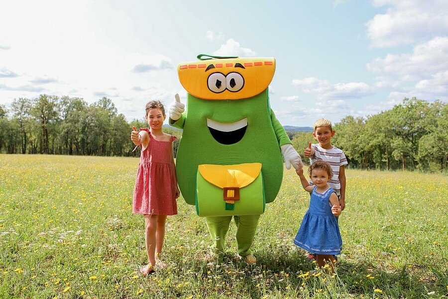 Smiling children with the campsite mascot during an Easter weekend in nature, family-friendly atmosphere with activities for kids.