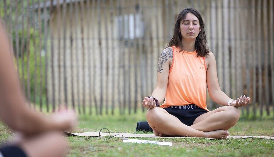 Holidaymaker meditating outdoors at a nature campsite with flexible Wednesday-to-Wednesday stays.