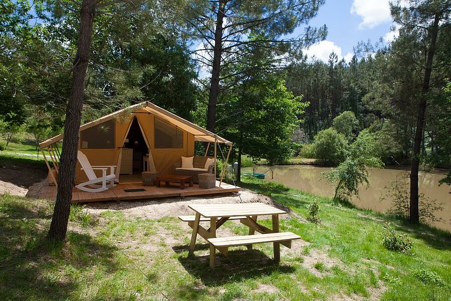 Lodge tent with furnished terrace, set in unspoilt nature by a pond on a campsite in the Périgord, in the Dordogne.
