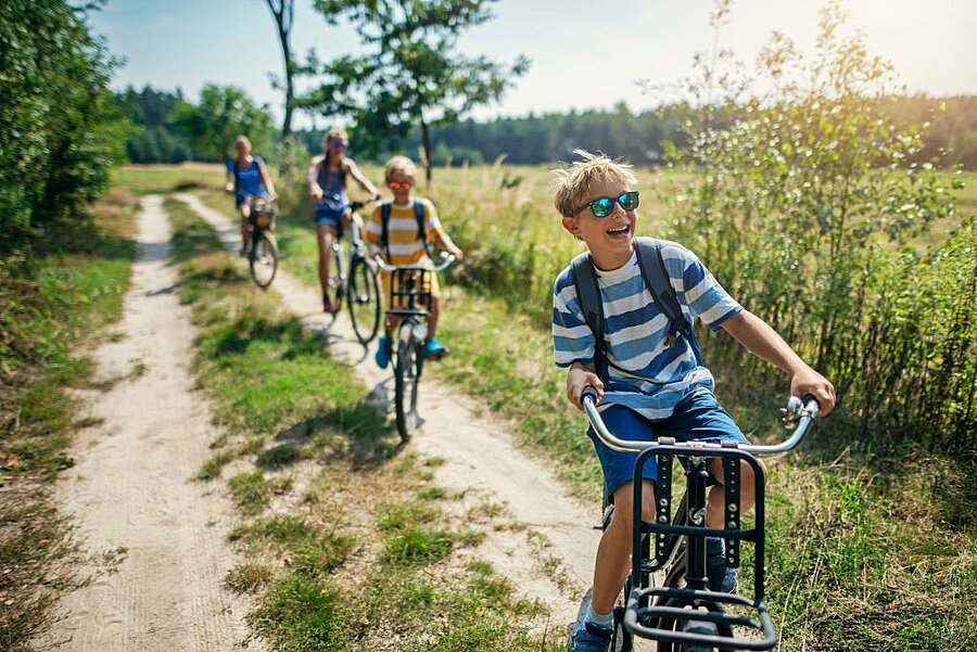 Smiling children biking on a country path in Loir-et-Cher, enjoying a family-friendly nature campsite