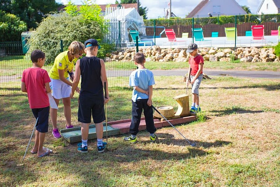 Children playing mini-golf under the watchful eye of a group leader at a family-friendly campsite near Sologne, in Gien.
