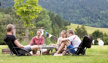 A family gathered around a game in the great outdoors, embodying the values of sustainable tourism featured in the responsible holidaymaker's guide by Sites et Paysages.