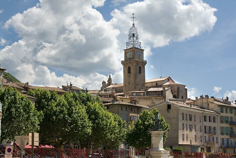 Historic center of Digne-les-Bains with bell tower and Provençal rooftops, spa town to visit during a camping holiday.