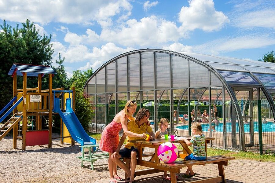 Family on holiday at a campsite in the Vosges with a playground and indoor pool, perfect for relaxing moments with the kids