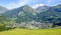 A small village nestled in the heart of the mountains in summer, surrounded by lush green countryside