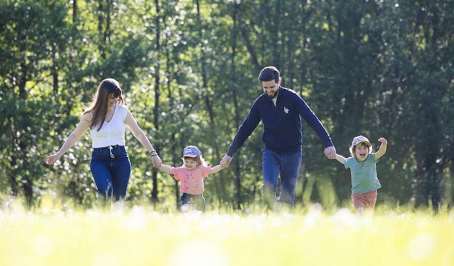 Family with children walking hand in hand in a natural campsite setting, perfect to book a family weekend.