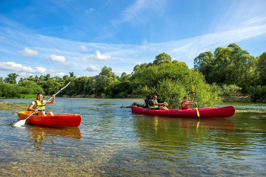 Family canoeing on a river surrounded by nature, enjoying activities thanks to waived booking fees at an affordable campsite.