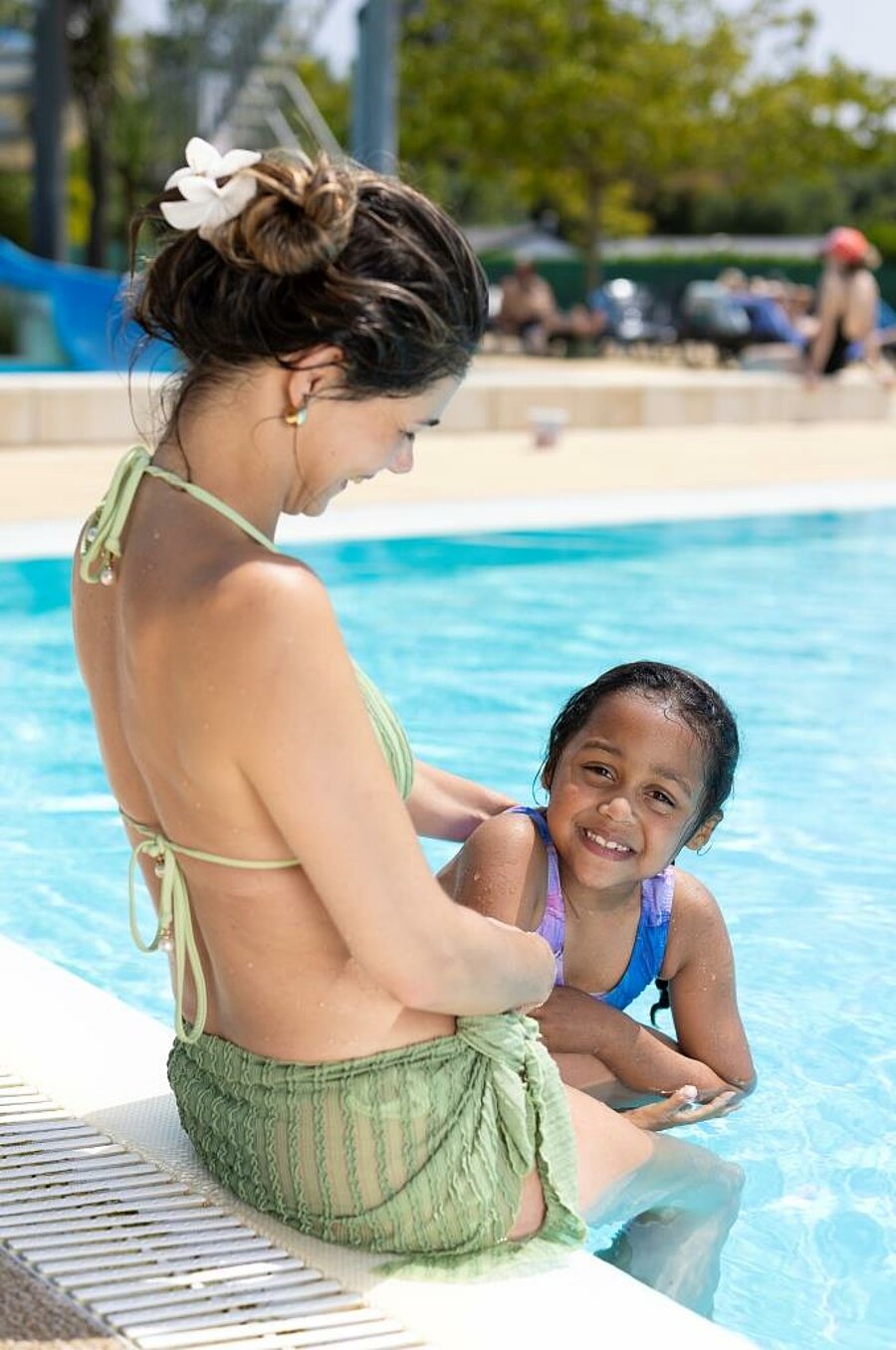 Child and mother in a pool at a 3-star campsite in France, friendly aquatic area for family holidays.