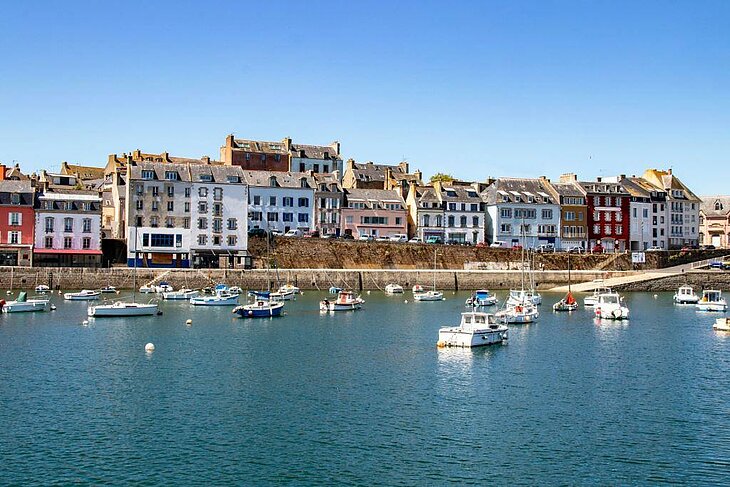 Pleasure boats moored in Douarnenez Harbour, with colourful houses in the background.