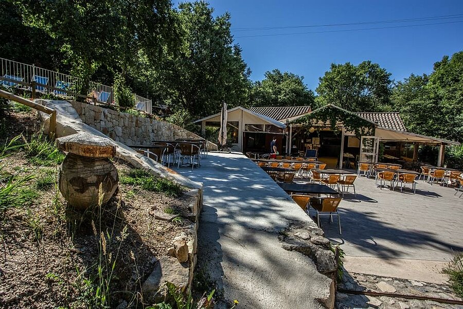 Shaded terrace of a restaurant in a campsite near Aubenas, perfect for relaxing and enjoying holidays in the heart of nature.