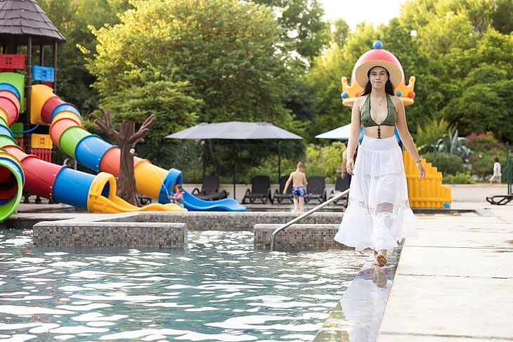 A holidaymaker walks beside the swimming pool at a campsite with water slides.