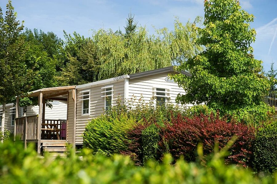Moblil-home surrounded by greenery at Camping Beauregard, a comfortable rental for a holiday near Lons-le-Saunier.