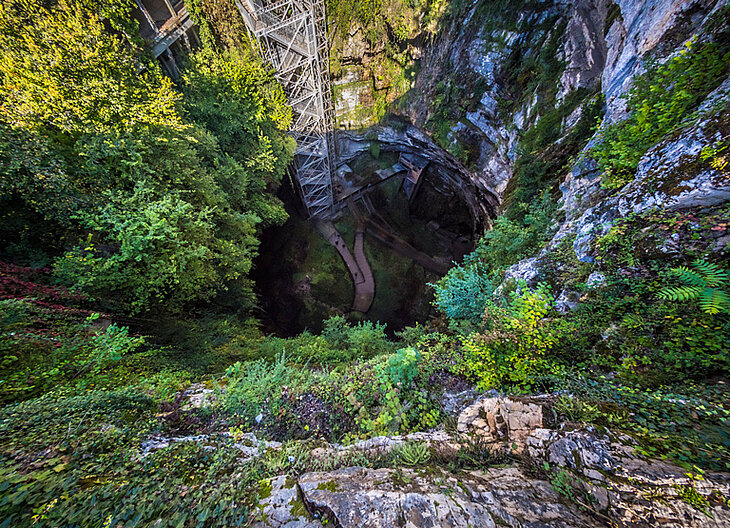 Bird’s-eye view of the Padirac Chasm, a spectacular cavity surrounded by cliffs and vegetation, a must-see underground site.