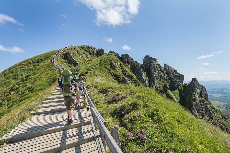 Hikers on the Puy de Sancy trail near Mont-Dore, breathtaking alpine panorama and endless Auvergne landscapes.