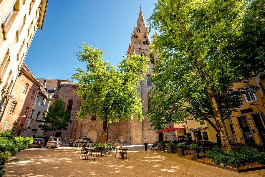 Shaded square with terraces at the foot of a Gothic church in old Grenoble, to enjoy during an urban or nature campsite stay.