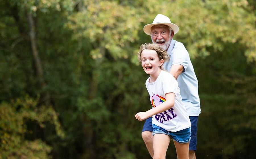 Grandfather and granddaughter joyfully running outdoors