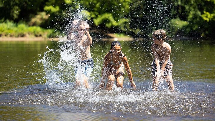 Children playing in a river in the heart of nature, a free activity ideal for affordable family holidays.