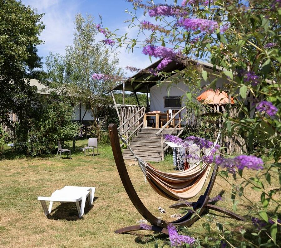 Glamping accommodation with terrace and hammock in a lush setting, perfect for a unique stay combining comfort and nature.
