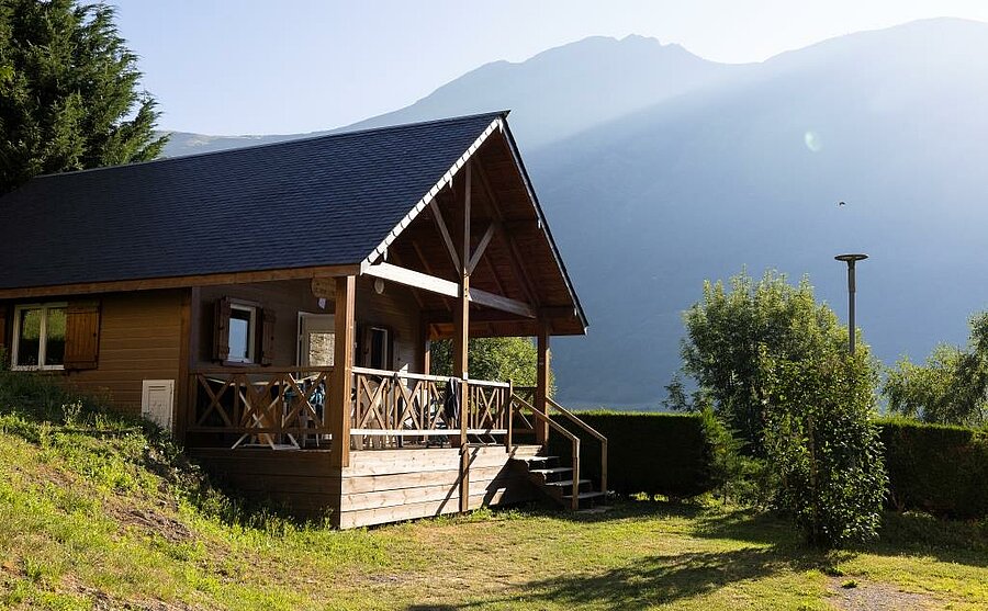 Wooden chalet with shaded terrace and mountain views in a peaceful campsite near Lourdes, in the Pyrenees.