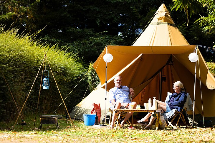 Couple enjoying a tent stay Couple enjoying a tent stay at Le Neptune campsite in Lanloup, set in a peaceful natural environment, reflecting local culture and heritage.