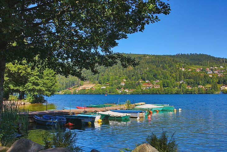 Boats moored on Lake Gérardmer, surrounded by lush green mountains — just minutes from Corcieux, an ideal destination for nature-based tourism.