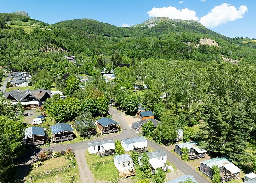 Green campsite with mobile homes and chalets, ideally located near Murol Castle in Puy-de-Dôme.