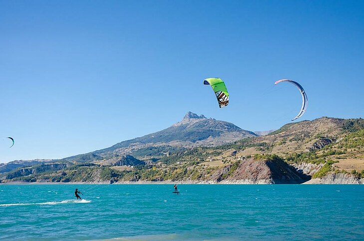 Kitesurfers on Lake Serre-Ponçon in Baratier, taking advantage of the favourable winds and the exceptional setting between the turquoise waters and the mountains of the Hautes-Alpes.