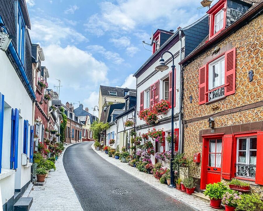 Paved street lined with colourful, flower-filled houses in Saint-Valery-sur-Somme, a historic area of the Baie de Somme.