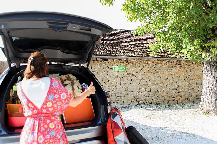 Guest arriving in an electric car at the parking area of a campsite with an EV charging station, starting an eco-friendly holiday.