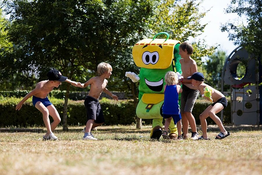 Group of children playing with a smiling mascot in a family-friendly campsite in Pays de la Loire, joyful atmosphere.
