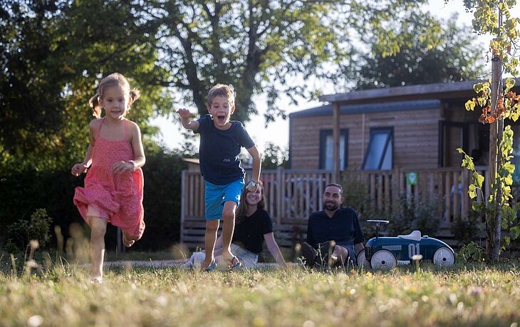 Children playing in front of a mobile home at a family campsite, ideal for affordable family holidays.