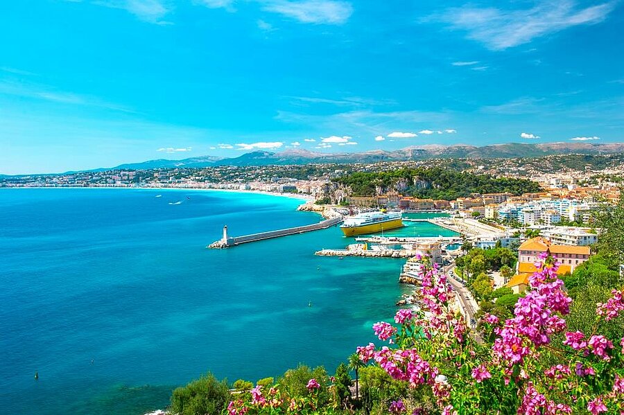View of Nice harbour, turquoise Mediterranean sea and surrounding hills with Mediterranean flowers, close to a campsite on the French Riviera.