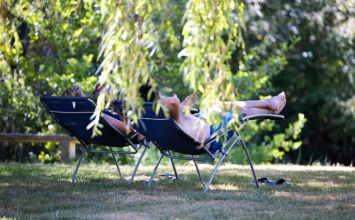 Couple lying on shaded loungers in nature, peaceful moment showing the benefits of early booking couple.