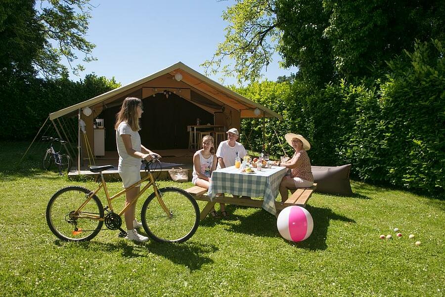 Family sharing a meal in front of a camping tent