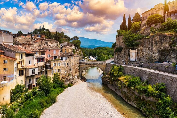 View of the Roman bridge, the Ouvèze River and the houses of Vaison-la-Romaine, with the Provençal hills in the background.