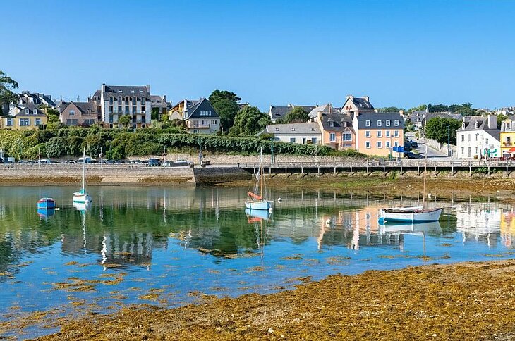 Boats moored in front of the pastel houses of Camaret-sur-Mer, a charming harbour village.