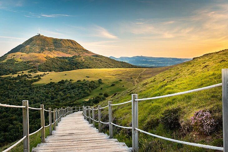 Panoramic view of the Puy de Dôme at sunset, an emblematic volcano in Auvergne-Rhône-Alpes, ideal for hiking and exploring volcanic landscapes