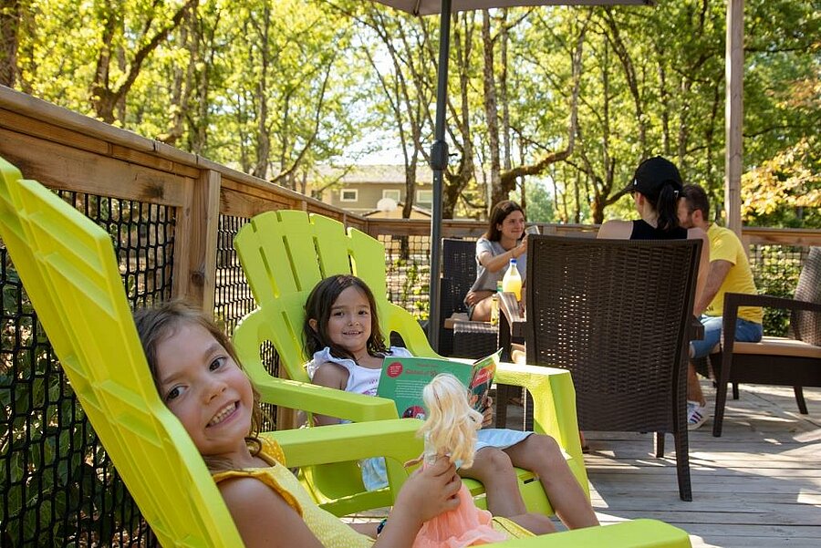 Children relaxing on a mobile home terrace, friendly atmosphere for a last minute August camping family holiday.