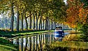 [Translate to Anglais:] Une péniche naviguant paisiblement sur le Canal du Midi bordé d’arbres, un cadre naturel idéal à proximité des campings Sites et Paysages.