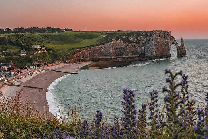 Sunset over the cliffs of Étretat in Normandy, with a natural arch overlooking the sea and a peaceful beach, a romantic idea for couples.